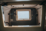 Bright camper van pop-top tent in an RV rental, showing an open window, fabric walls, and securing straps.