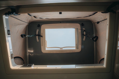 Bright camper van pop-top tent in an RV rental, showing an open window, fabric walls, and securing straps.