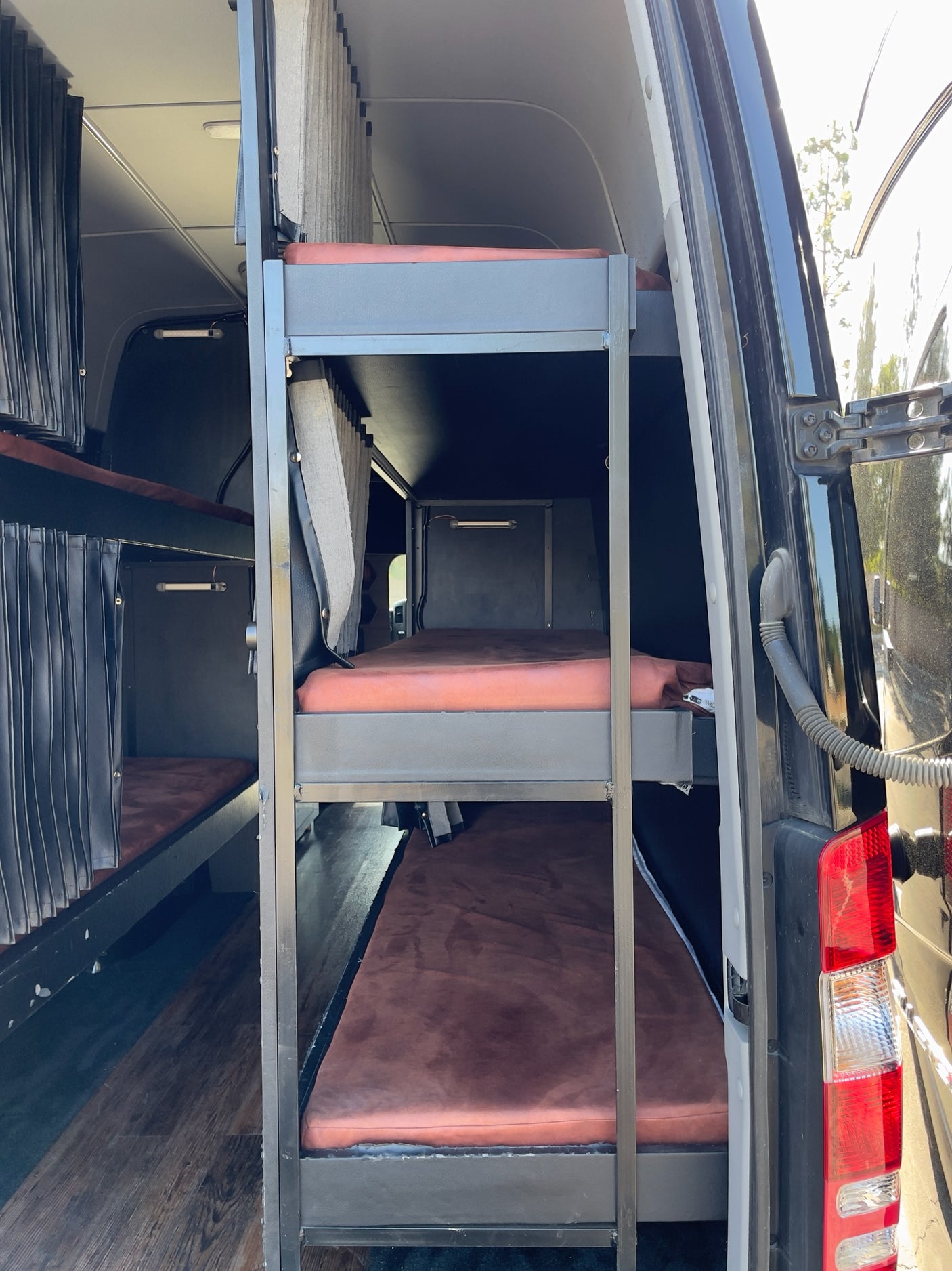 This RV rental's custom interior features multi-level bunk beds with privacy curtains, ideal for group travel.