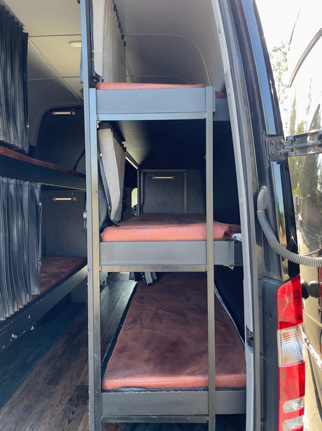 This RV rental's custom interior features multi-level bunk beds with privacy curtains, ideal for group travel.