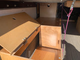 Inside an RV rental: custom-built plywood storage/bed platform with an open lid, revealing an organized camper van interior.