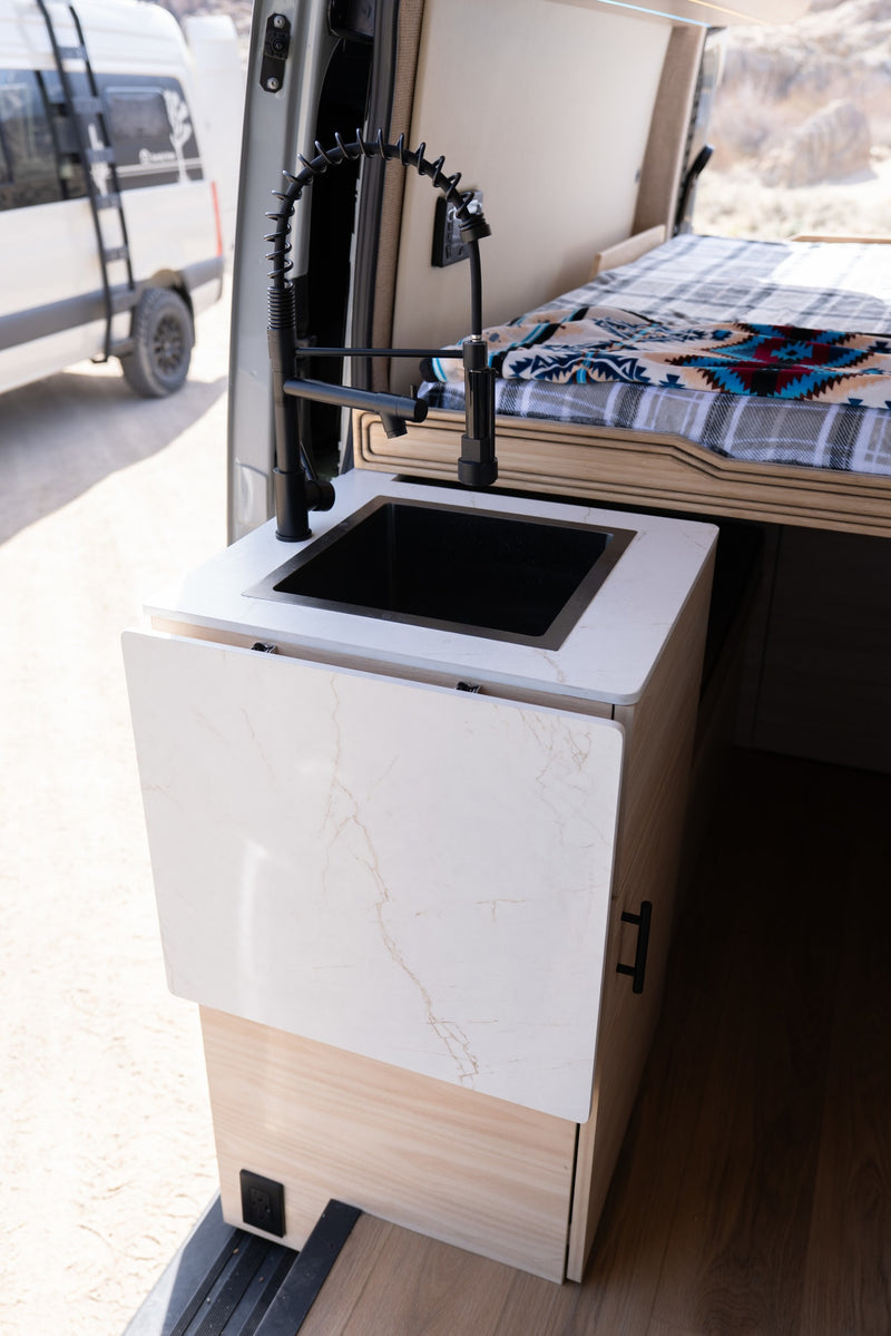  parked off-road with stunning snow-capped mountains in the background.|Modern RV rental interior: A kitchenette featuring a black sink — photo 4