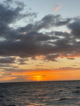 Golden sunset over calm ocean waves & clouds. A perfect end to an RV rental day.
