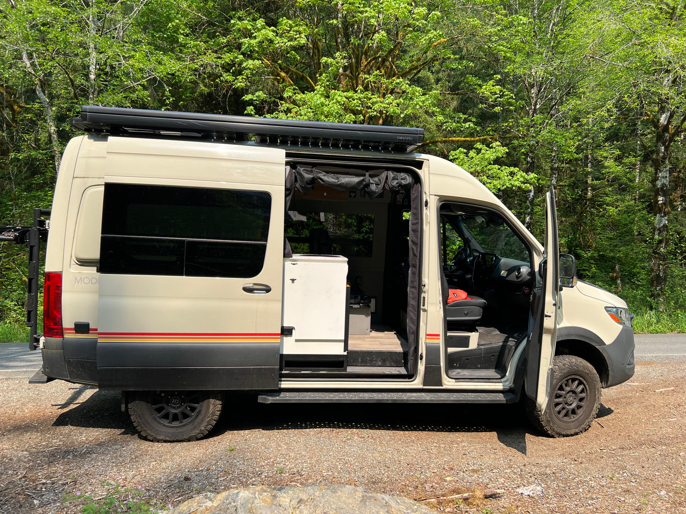 Light-colored camper van RV rental parked roadside. Side door open reveals interior for outdoor travel. — photo 11