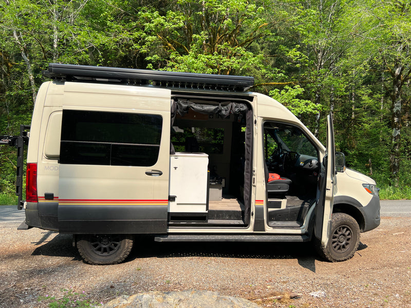 Light-colored camper van RV rental parked roadside. Side door open reveals interior for outdoor travel. — photo 11
