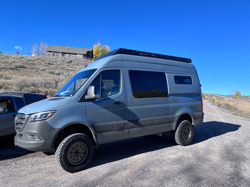 with a doll lying on the sandy bank.|Grey Mercedes-Benz Sprinter rv rental camper van on a gravel road — photo 2