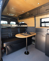 Inside this RV rental: an elevated bed, comfy bench dinette with a bamboo table, and a compact kitchen. Ideal for road trips.