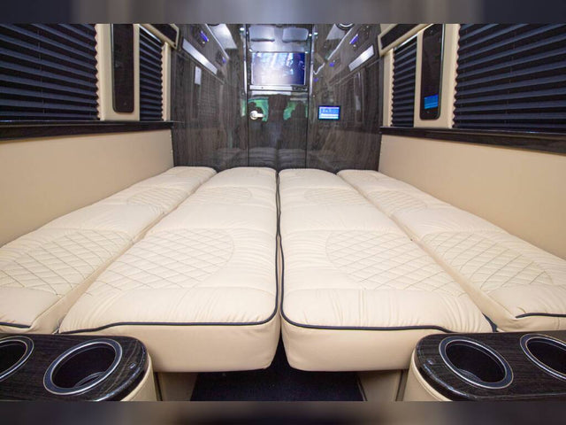  amidst green trees.|Inside a modern rv rental: cream quilted leather seats