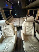 Luxurious RV rental interior featuring plush cream seats and a convertible bed, perfect for comfortable travel.