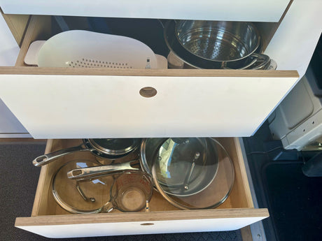 Compact rv rental kitchen with organized drawers. Cookware, pots, pans, colander & measuring cup neatly stored.