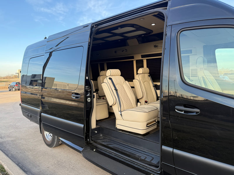 Black luxury rv rental van with its side door open, showing a plush, cream-colored interior and quilted captain's chairs. — photo 2