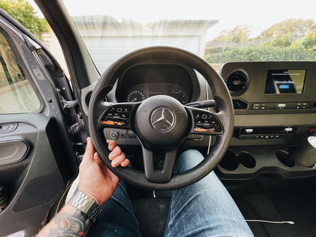 Inside a Mercedes-Benz Sprinter van, showing the dashboard from a driver's perspective. Ready for an RV rental trip.