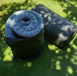 RV rental essential: Comfy sleeping pad rolled in its bag & an inflatable mattress on synthetic grass for your outdoor comfort.