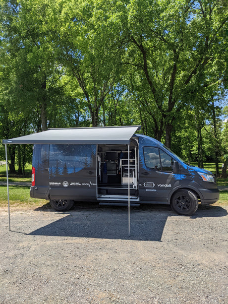 Custom vandoit camper van with starry graphics, awning, and open door. An RV rental perfect for nature trips.