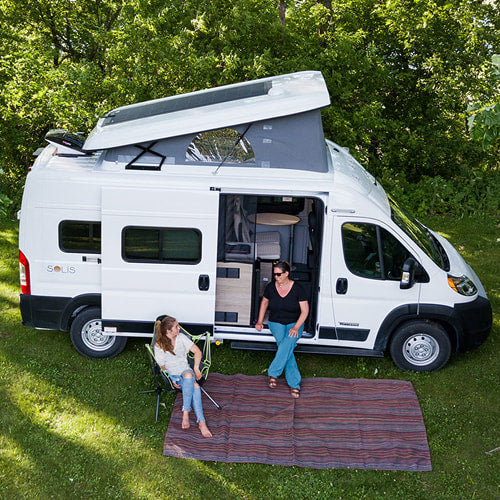 Two women relaxing outside a white pop-top campervan, ideal for your next RV rental camping trip.