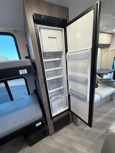 Inside an RV rental: a full-size refrigerator with freezer, a 220 lbs capacity bunk bed, and a comfortable lounge area.