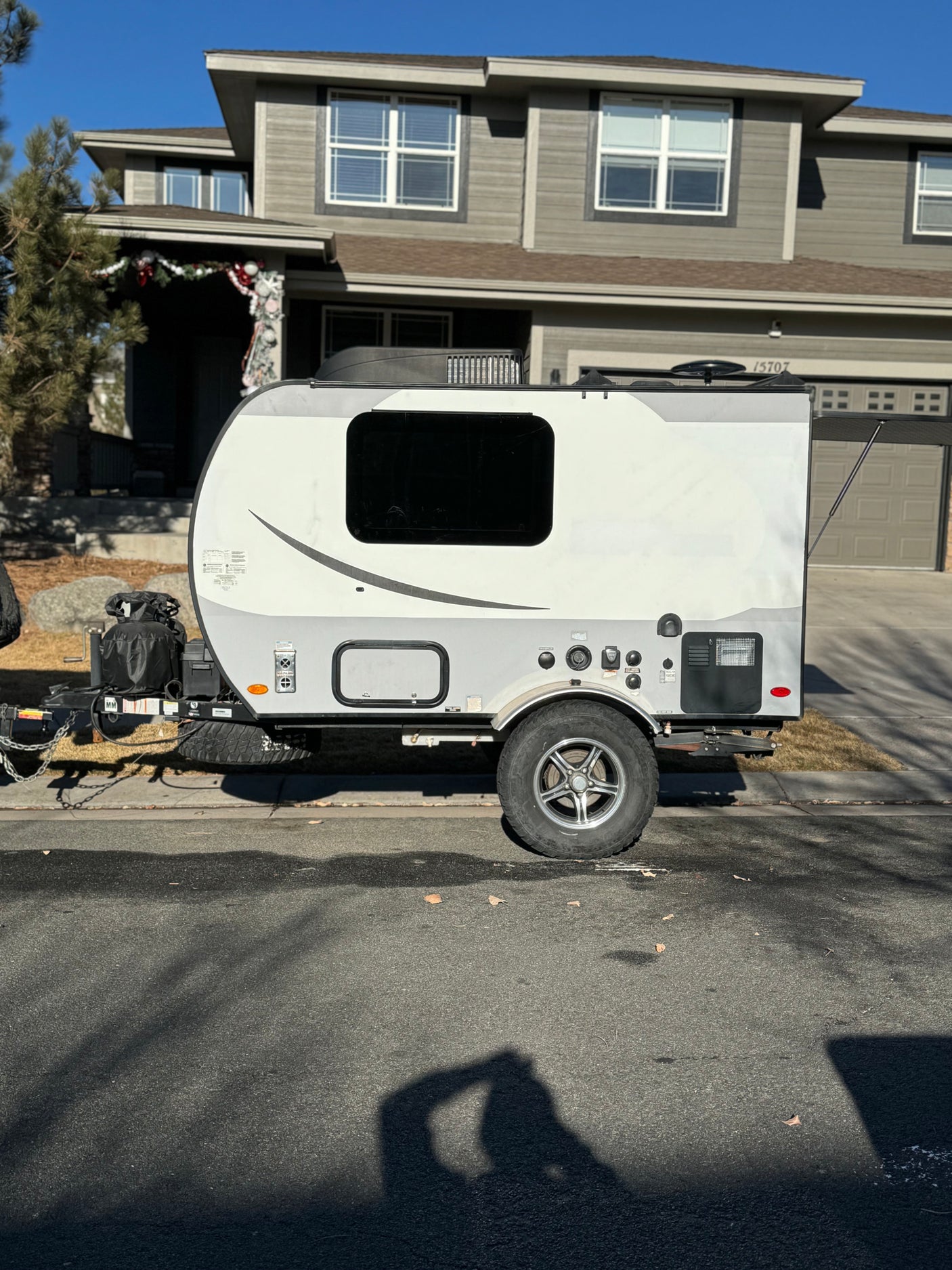 Compact white and grey teardrop RV rental parked curbside. This small travel trailer is ready for your next outdoor adventure.