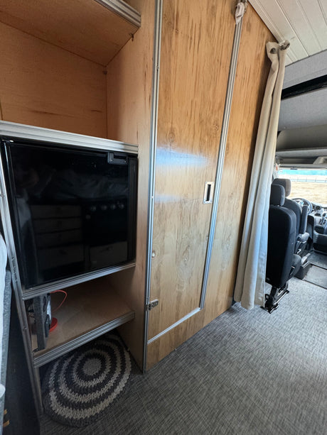 Inside a spacious RV rental: custom wood cabinets, integrated fridge, and front cabin view for your road trip adventure.