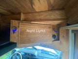 Inside an RV rental, custom wood interior features blue night lights illuminating the cozy cabin above the dashboard.