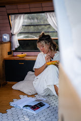 Relaxed woman enjoys papaya in a cozy RV rental, sitting on a unique hex-tiled floor with a book.