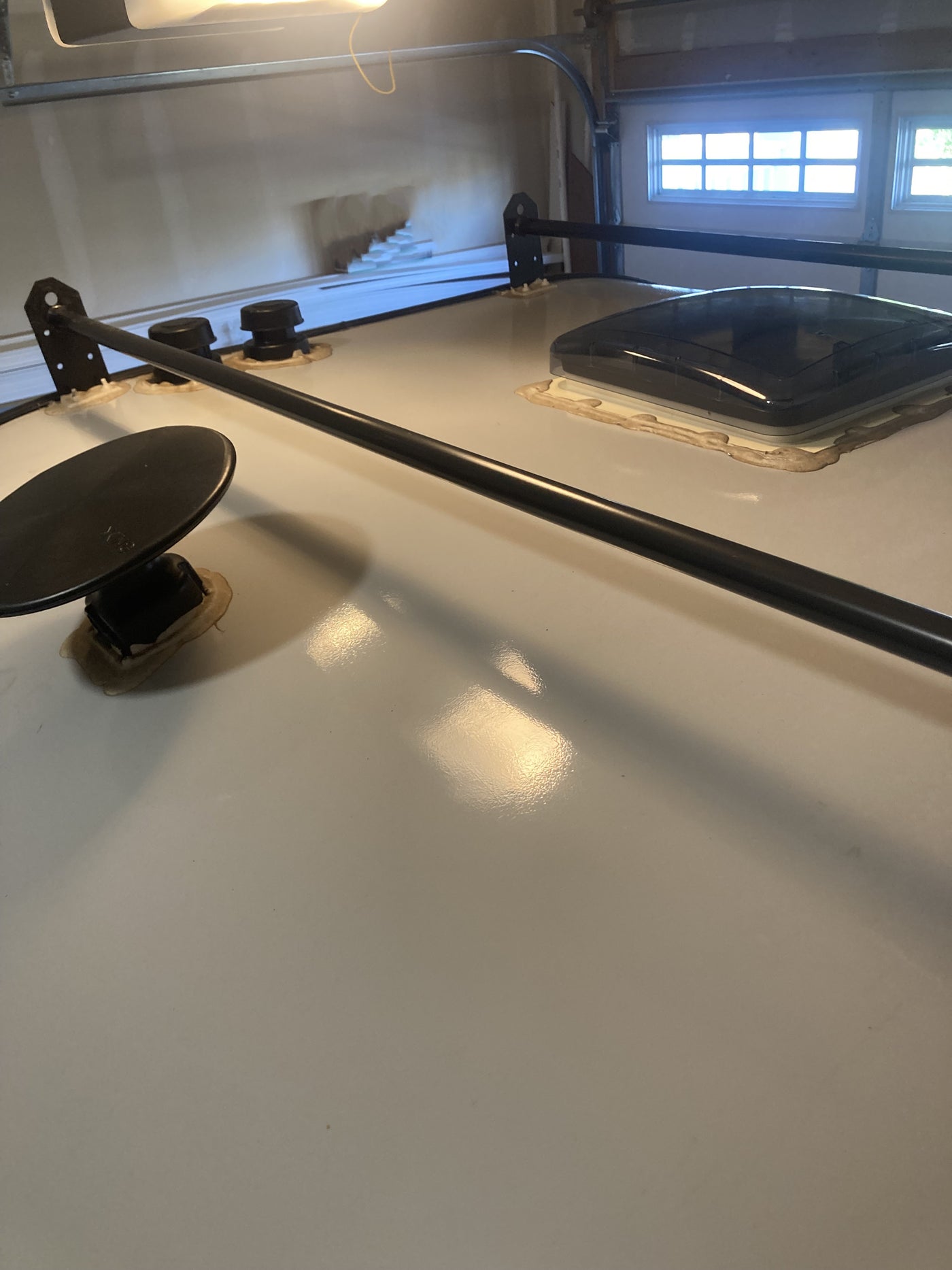An RV rental's roof in a garage, featuring a roof rack, vent, and other sealed components. — photo 16