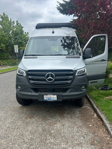 Front view of a silver Mercedes-Benz Sprinter Winnebago rv rental van, door open. Washington plate CPH8151 on a cloudy day.