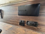 RV rental interior: electrical panel, 12V outlets, and CO detector mounted on a wood-grain wall for safety and power.