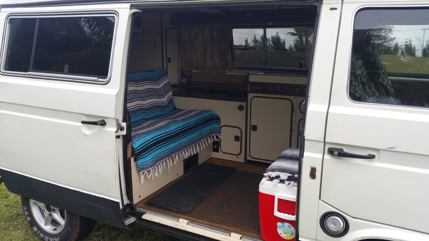 White camper van RV rental with open side door revealing a compact interior, ideal for adventurous road trips.