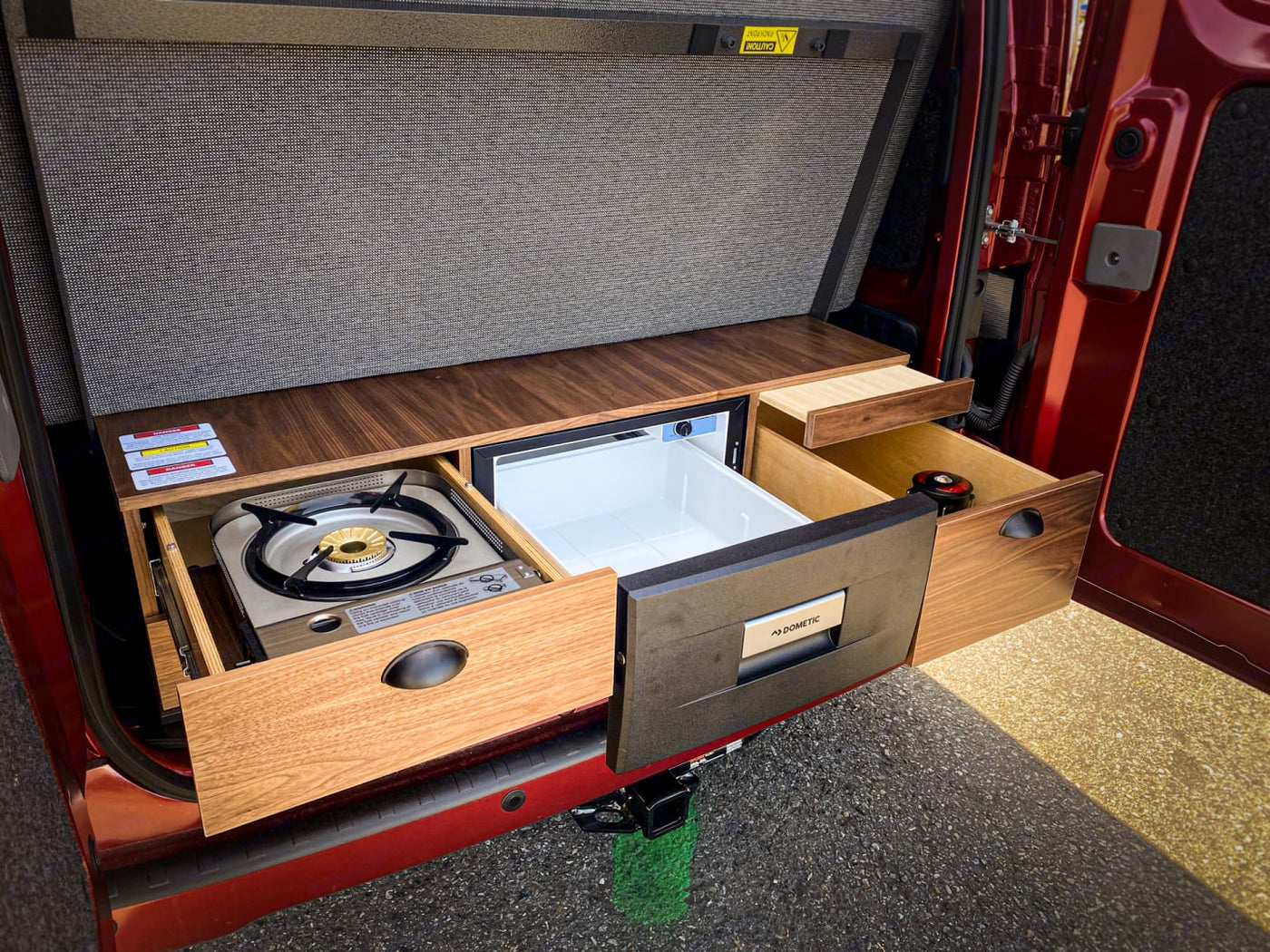 RV rental's clever kitchen: pull-out stove, Dometic fridge, and wood drawers for compact van living. — photo 4