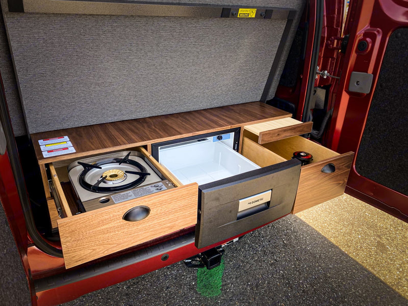 RV rental's clever kitchen: pull-out stove, Dometic fridge, and wood drawers for compact van living. — photo 4