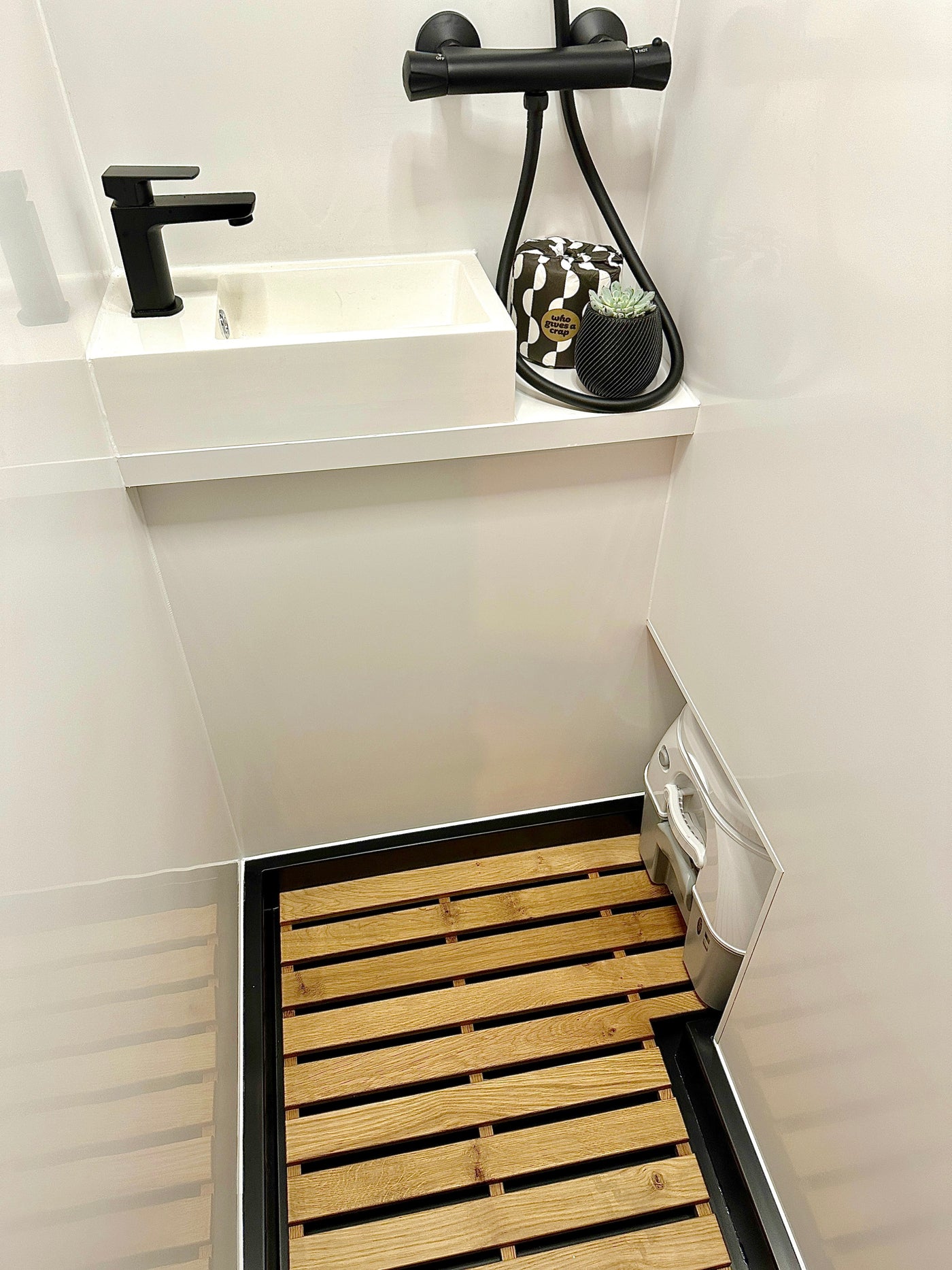 Modern RV rental wet bath, featuring a sleek black sink, shower, and discrete portable toilet on a wooden slatted floor. — photo 15