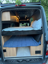 RV rental camper van interior shows stacked beds, wood cabinetry, and recessed lighting, ideal for adventurous travel.