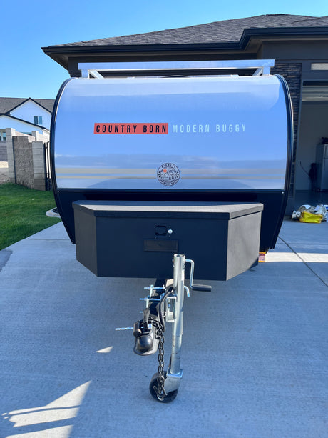 Front view of a sleek, silver and black 'COUNTRY BORN MODERN BUGGY' travel trailer, perfect for your next RV rental adventure.