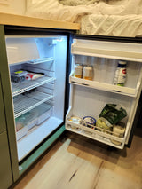 An RV rental's mini-fridge, neatly stocked with travel essentials like berries, bacon, drinks, yogurt, and salad.