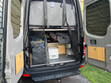 RV rental ready for adventure! Rear van view shows organized storage, bed, portable toilet & outdoor shower.