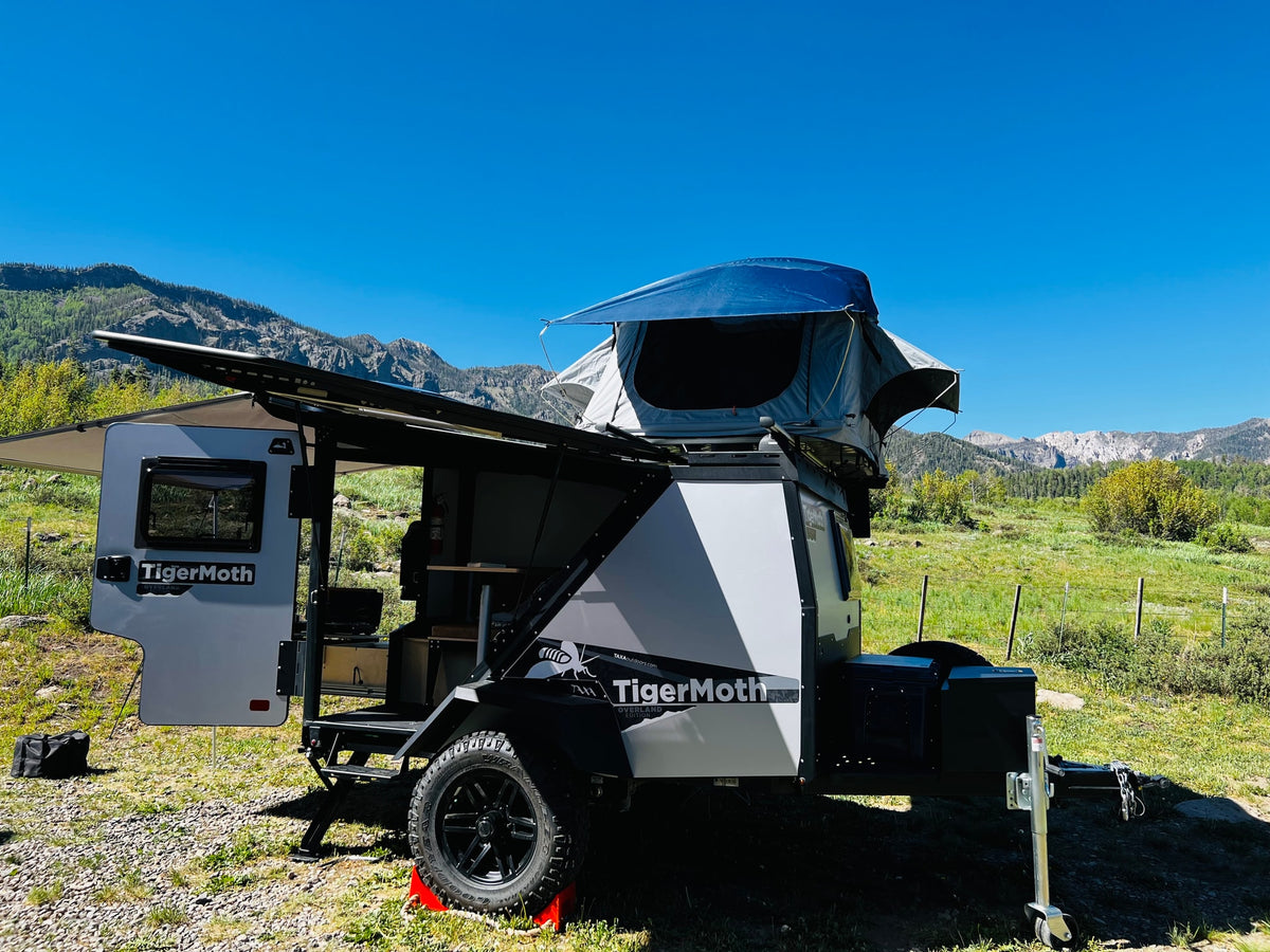 Enjoy a TigerMoth overland trailer RV rental, featuring a rooftop tent, set up for camping in a scenic mountain landscape. — photo 4