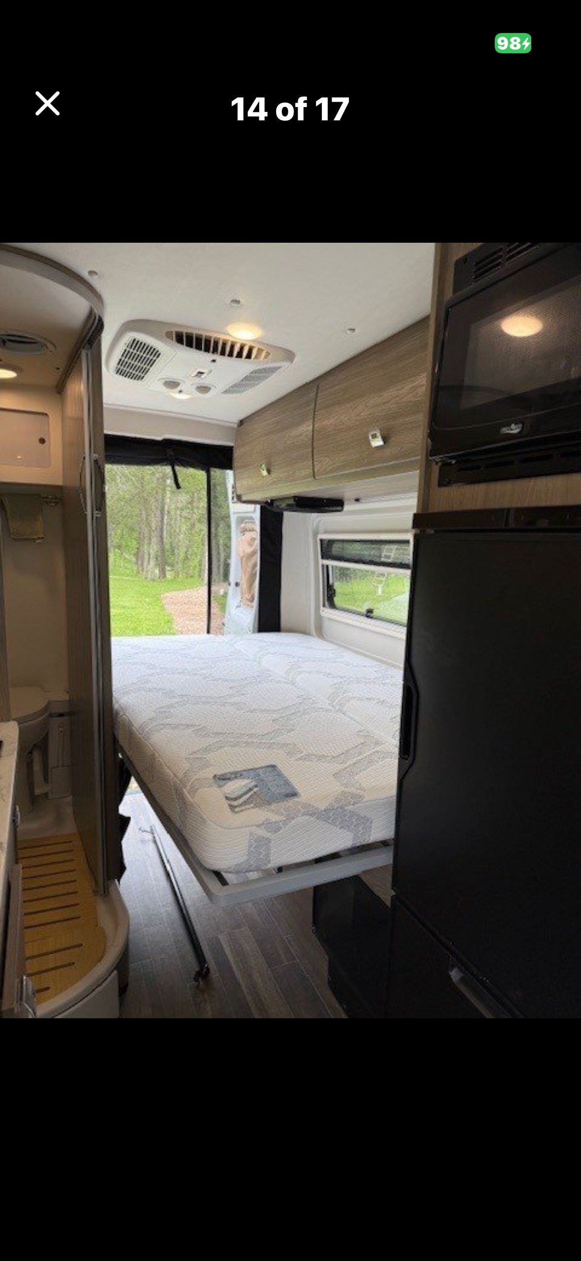 Comfortable RV rental interior featuring a fold-down bed, compact bathroom, and kitchen appliances. Perfect for travel.