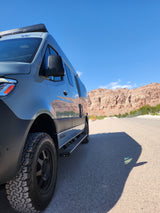 A modern grey RV rental with off-road tires, parked on an