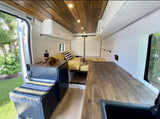 Inside a spacious custom RV rental, a comfy bed, wood-paneled ceiling, and two relaxing dogs enhance the inviting interior.