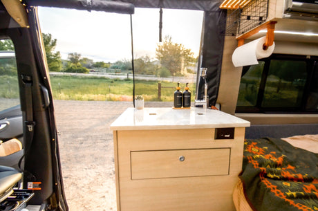RV rental interior: cozy camper van with a compact kitchen, sink, and an outdoor view. Perfect for a road trip adventure!