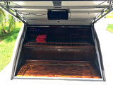 Inside a custom RV rental compartment: a wood interior with a speaker, control panel, and storage space.