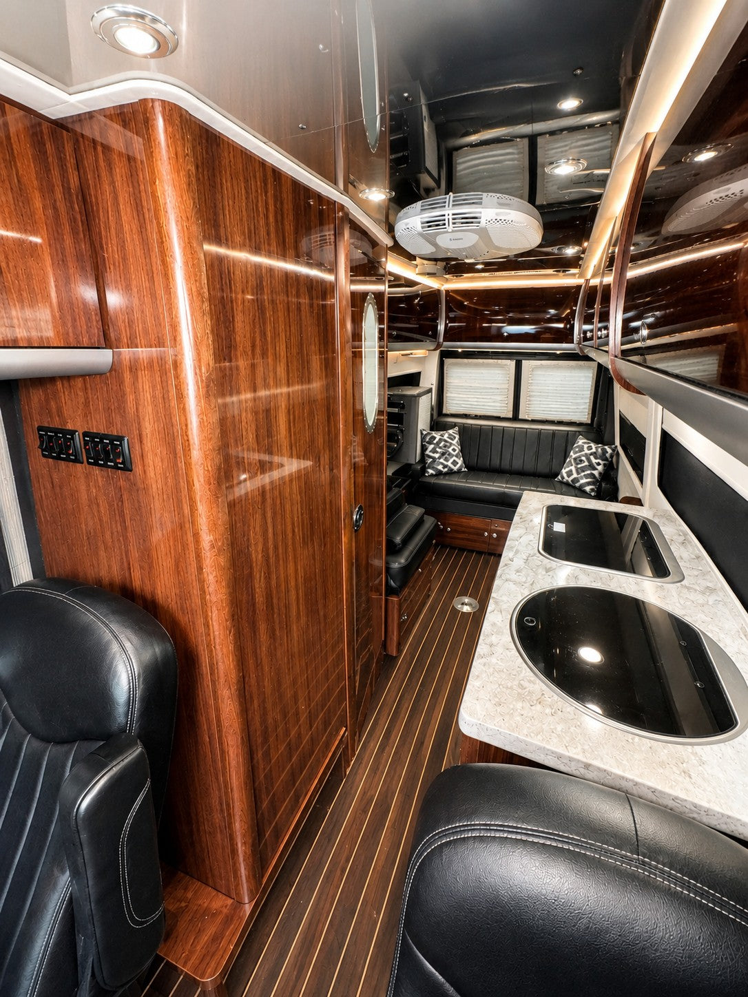  and cozy living space. Perfect camper van for travel.|Luxury **rv rental** interior: a large black leather sofa — photo 3