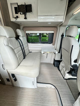 Bright RV rental interior features comfy bench seating, a practical fold-down table, and a wall-mounted entertainment setup.