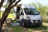 A white Carado camper van, ideal for rv rental adventures, parked under a tree with an awning & picnic table at a campsite.