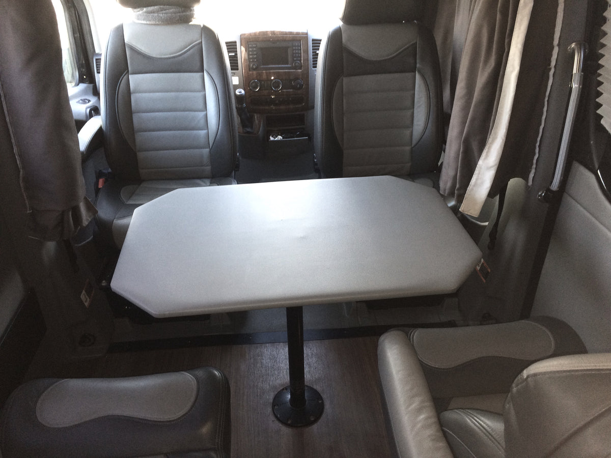 RV rental interior featuring comfortable front seats, a central table, and cozy rear seating. Ideal for travel! — photo 11
