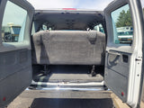 Open rear of a white van, showing a gray bench seat and spacious interior. Ideal for an RV rental conversion or transport.
