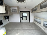 Compact rv rental interior featuring a comfy sleeping area, AC, door, and mesh storage. Ideal for adventurers.