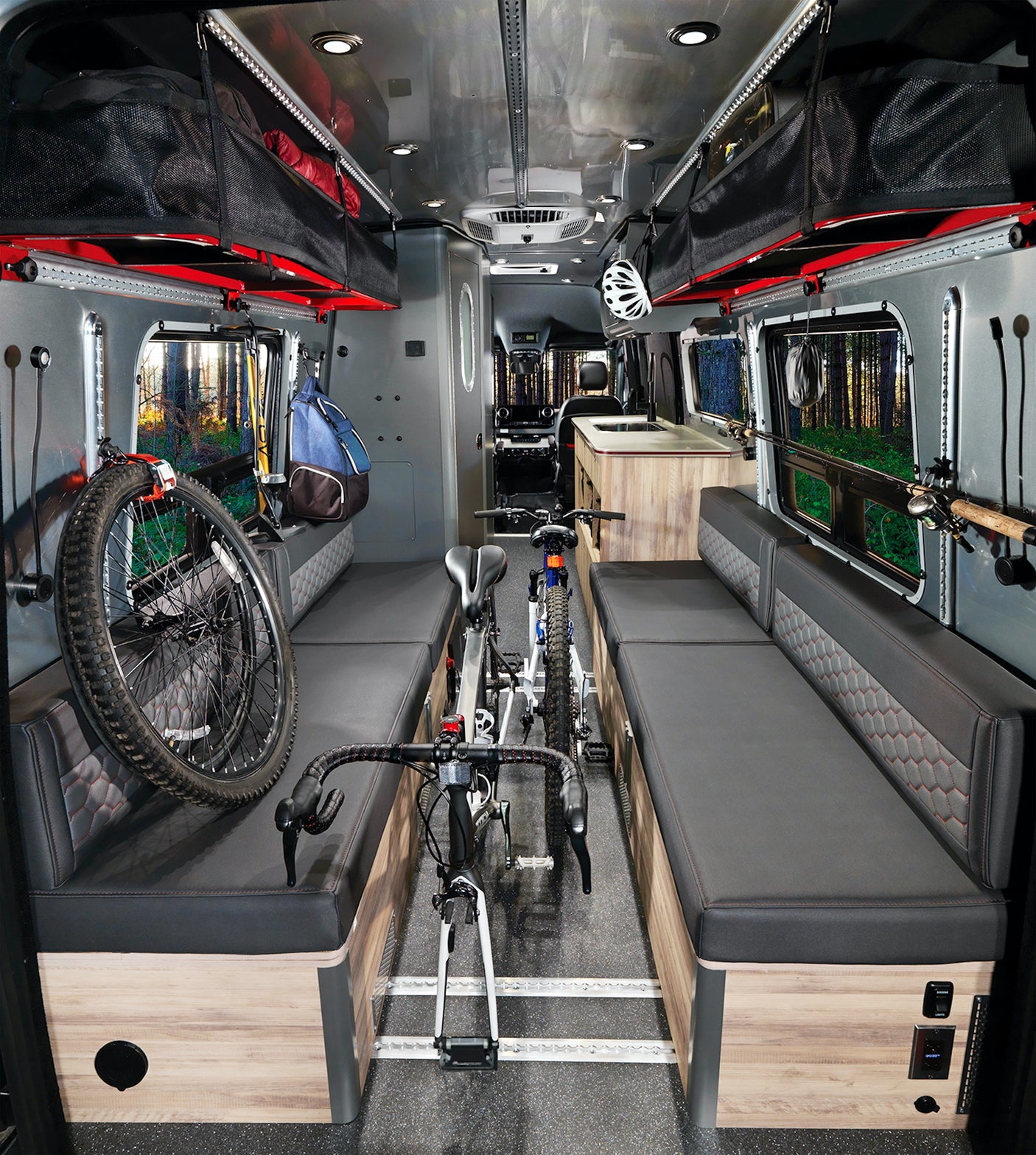 Adventure-ready RV rental: a versatile camper van interior with bike & gear storage, comfy benches, and forest views.