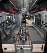 Adventure-ready RV rental: a versatile camper van interior with bike & gear storage, comfy benches, and forest views.