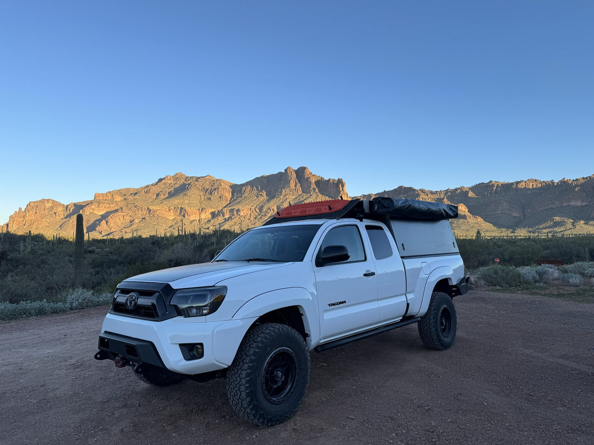 Adventure-ready white Tacoma truck camper for desert overlanding. Explore mountains & saguaros; perfect for an RV rental trip!